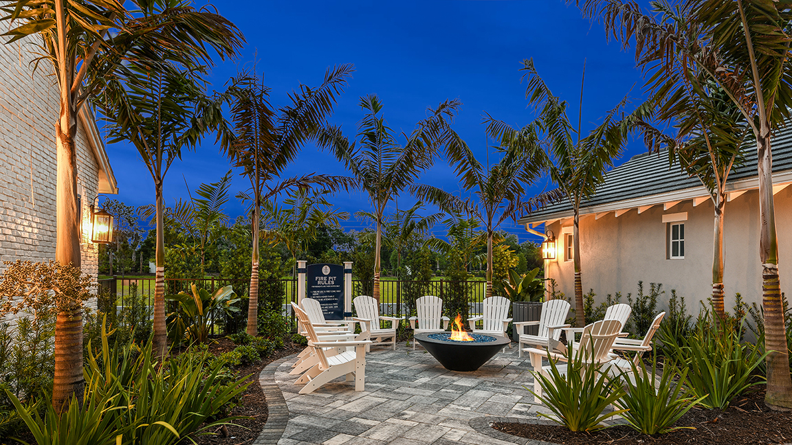 Fire pit lounge ringed by royal palms at blue hour — Canoe Creek Amenity Center